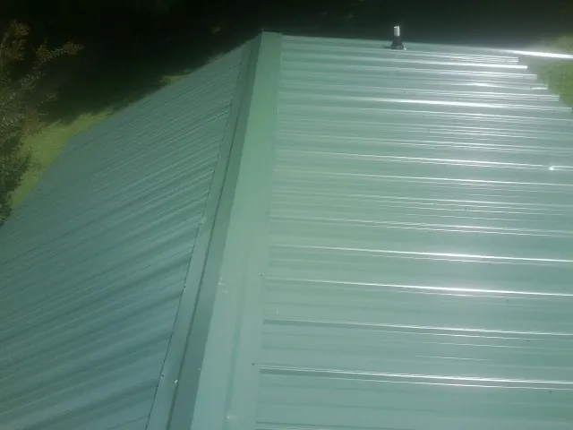 New green metal panels meeting at the ridge of a roof — Flat Roof Repair work by our crew in Rush Valley