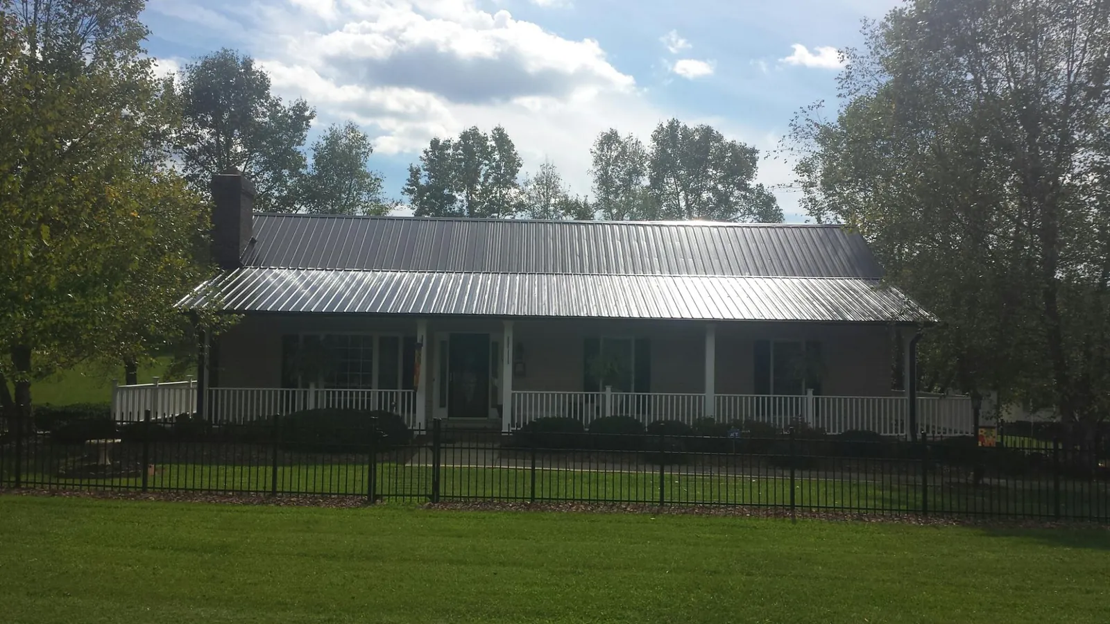 Gray metal roof on a brick ranch with a full width front porch — Gutter Guard Installation work by our crew in Rush Valley