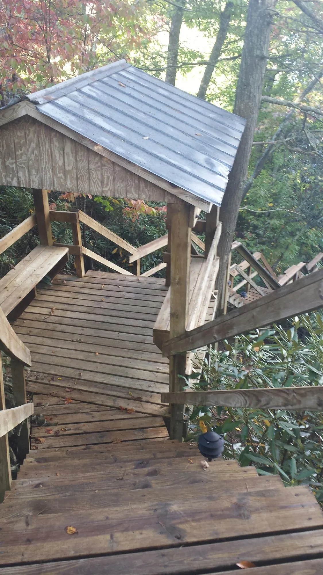 Metal roofed shelter over wooden steps on a wooded walkway — Skylight Repair & Installation work by our crew in Rush Valley